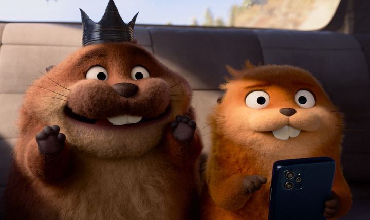 Two beavers smile off into the middle distance. One looks a little shocked. The one on the left is wearing a crown made of a tin can and the one on the righti s holding a phone.